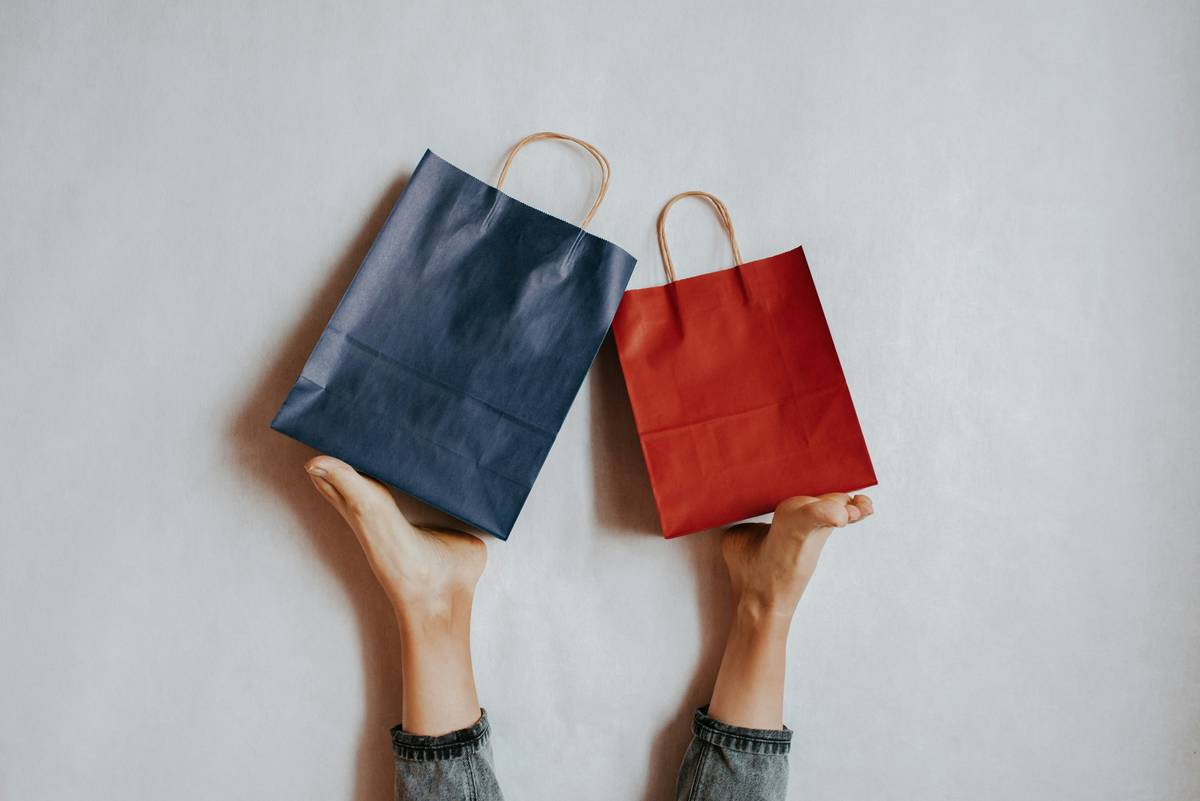 Happy woman holding on feet shopping package. Paper bag. Sale in store. Fashion shop creative advertisement. Customer buy present. Black friday sale. Holiday special offer, discount. Season deal